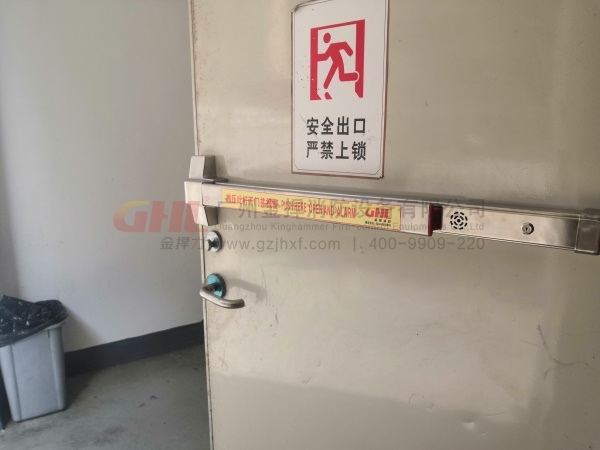 逃生門(mén)鎖警示標(biāo)識(shí)，與錚亮的不銹鋼鎖體形成強(qiáng)烈對(duì)比